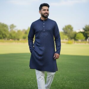 A man wearing a traditional kurta set walking confidently on a grassy field.