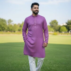A man wearing a traditional embroidered kurta with straight trousers, walking confidently on a grassy field.