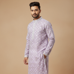 A man models a light lavender kurta with a subtle white geometric pattern, paired with white churidar pants and brown sandals.
